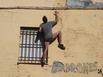Rear view of young man climbing wall