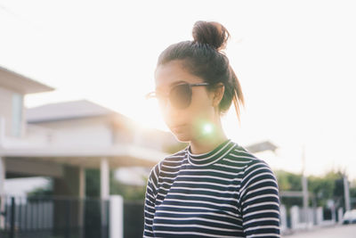 Young woman wearing sunglasses by building against sky