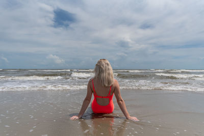 Rear view of young woman relaxing on shore at beach