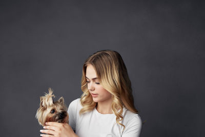 Portrait of young woman with dog against black background