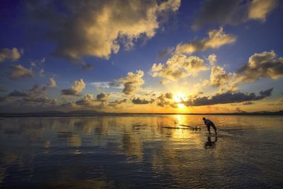 Man in sea against sky during sunset