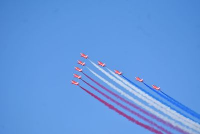 Low angle view of airplanes flying against clear blue sky