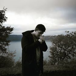 Man standing by tree against sky