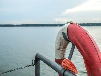 Lifeguard hanging on railing at sea against sky