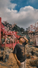 Young man standing against trees and plants against sky