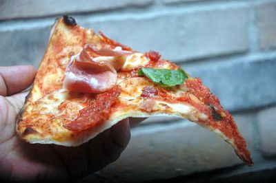 Close-up of hand holding pizza