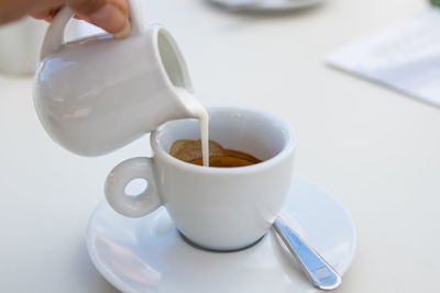 Cropped hand holding coffee on table