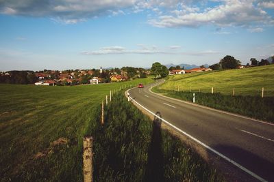 Road amidst field against sky