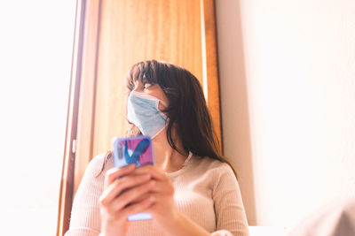 Portrait of woman holding mobile phone at home