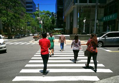 Rear view of people walking on road in city