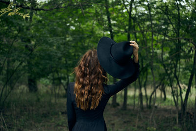 Rear view of woman standing in forest