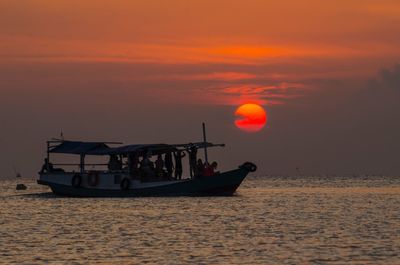 Boat sailing on sea against orange sky