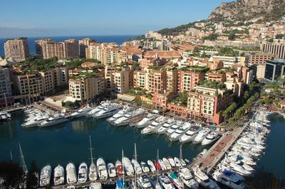 High angle view of boats moored at harbor against buildings in city