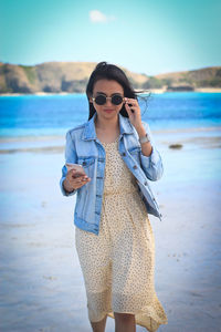 Young woman wearing sunglasses standing on beach