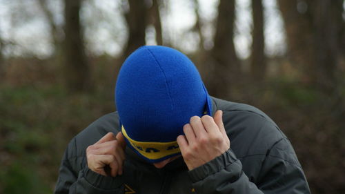 Close-up of man putting hat on