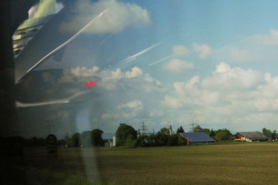 Trees on field against cloudy sky