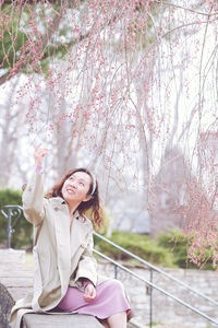 Portrait of young woman sitting on tree