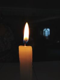 Close-up of lit candle in darkroom