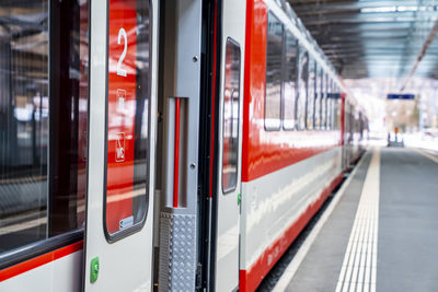 Open door of train arrived at platform on railroad station during sunny day