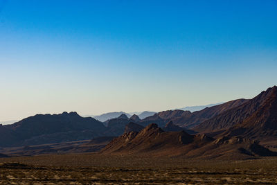 Scenic view of desert against clear blue sky