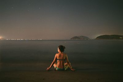 Full length of shirtless man on beach against clear sky