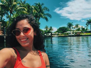 Portrait of smiling young woman in sunglasses against sky