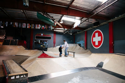 Wide shot of skateboard instructor holding hands with student