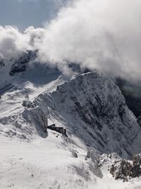 Scenic view of snow covered mountain covered in clouds 