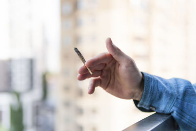 Midsection of person holding cigarette