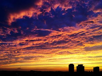 Silhouette of building against cloudy sky at sunset