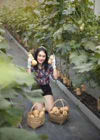 High angle portrait of smiling woman picking vegetables in farm