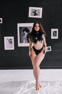 Portrait of young woman standing against wall