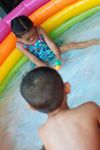 Brother and sister playing with balls in wading pool