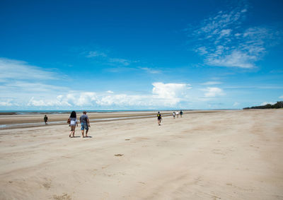 People on beach against blue sky