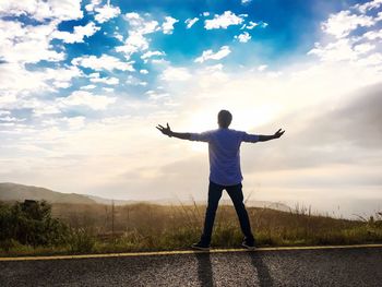 Woman with arms outstretched against sky