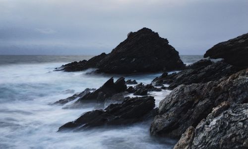 Scenic view of rocks on beach against sky