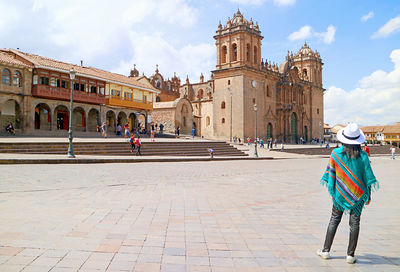 Rear view of woman walking on street by historic building