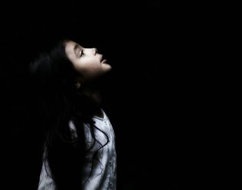 Close-up of young woman against black background