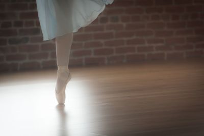 Low section of woman practicing tiptoeing in dance studio