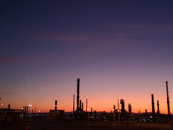 Silhouette factory against sky during sunset