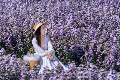 Rear view of woman standing amidst flowers