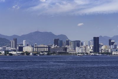 Sea by city buildings against sky