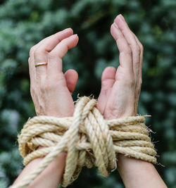 Close-up of hand holding rope tied to metal