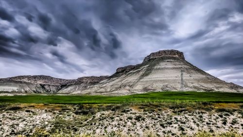 Built structure on landscape against cloudy sky