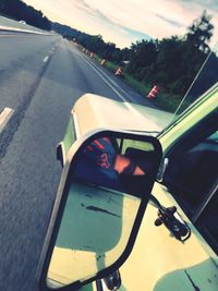 Reflection of man on side-view mirror of car