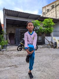 Full length portrait of boy holding while standing against built structure