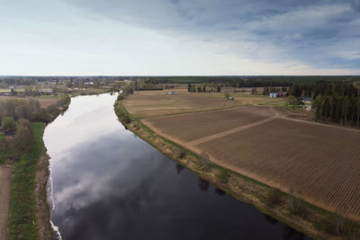 Stormy clouds gather over the river and the fields around it at the rural finland.