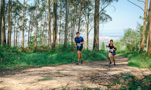 People running on street amidst trees in forest