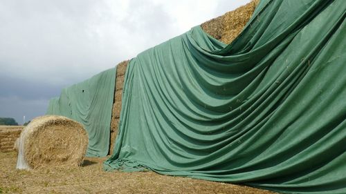 Stack of hay bales on field against sky