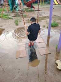 Rear view of boy in puddle